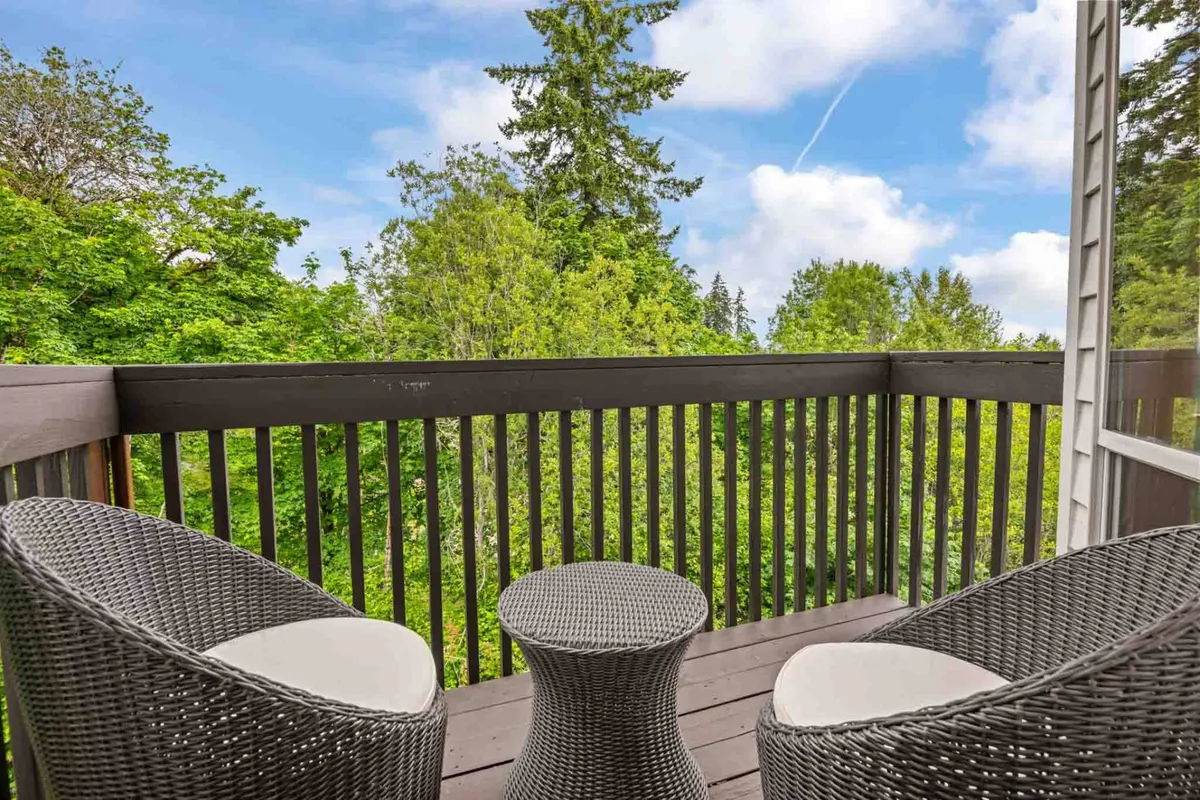 A tranquil outdoor seating area set with wicker chairs and a small round table, surrounded by lush greenery. The space evokes a sense of peaceful relaxation and connection to nature.