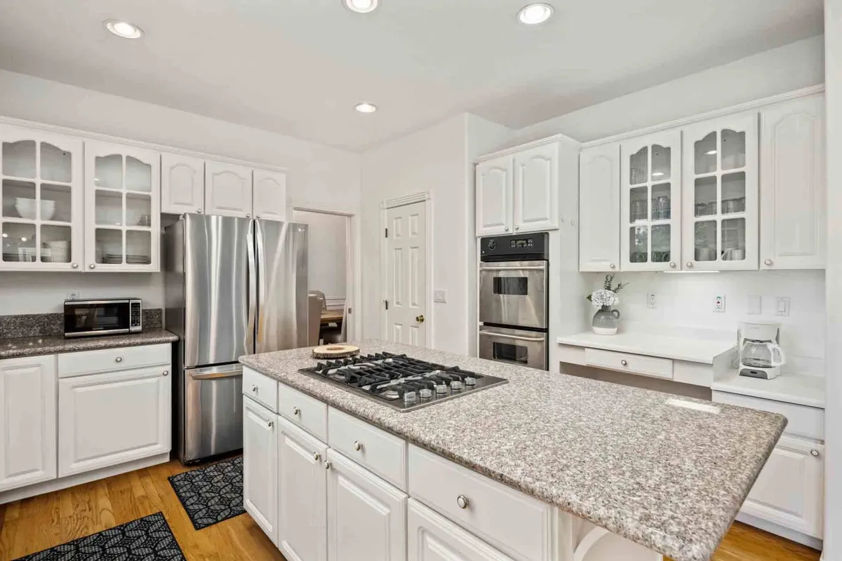 A bright kitchen with gleaming granite countertops, stainless steel appliances, and a spacious island. The inviting setup is ideal for hosting dinner parties and family cooking sessions, with enough room for multiple cooks to collaborate.