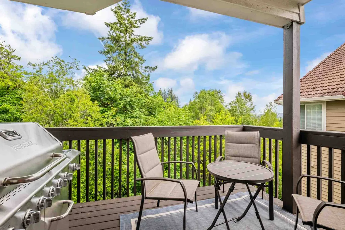 This exterior image features a grill and outdoor seating surrounded by lush greenery, creating a tranquil environment ideal for both relaxation and inspiration. The outdoor space is welcoming, with ample seating for enjoying fresh air, working outside, or taking a break from professional tasks. The green views reinforce the connection to nature and a peaceful ambiance.